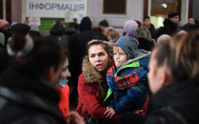 A woman carries a child at the train station in Lviv, western Ukraine, 3 March, 2022.