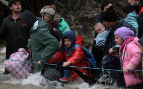 Refugees cross a river on their way to Macedonia from a makeshift camp at the Greek-Macedonian border.