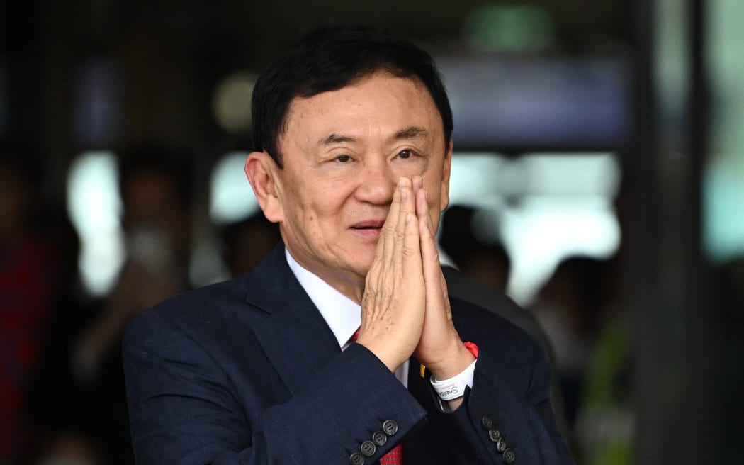 Former Thai Prime Minister Thaksin Shinawatra greets his supporters after landing at Bangkok's Don Mueang airport on August 22, 2023. Thaksin Shinawatra bowed in homage to the Thai king's portrait as he returned to the kingdom Tuesday after 15 years in exile, before being led away by officials to be processed on multiple outstanding criminal cases. (Photo by Manan VATSYAYANA / AFP)