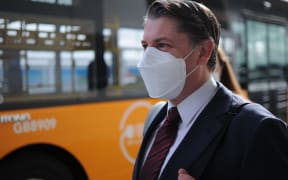 Minister of Transport Michael Wood waiting to catch an AirportLink bus to Puhinui Station Interchange on Friday.