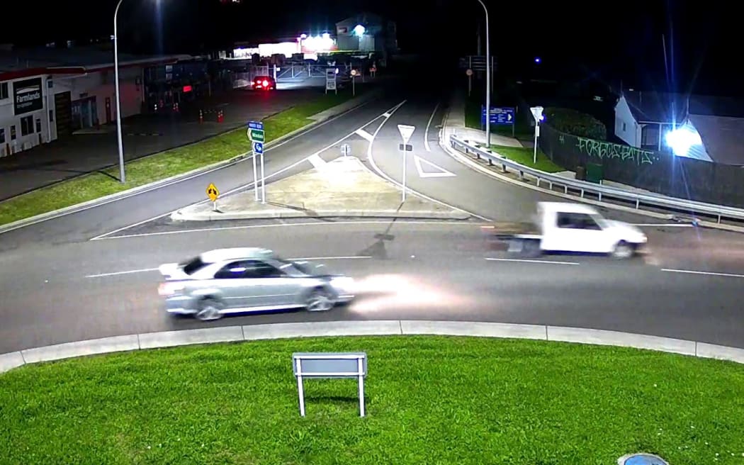A silver sedan and a white ute are seen driving at night.