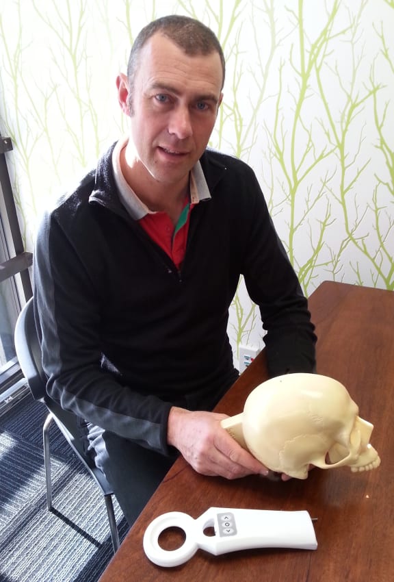 A photo of Simon Malpas with a wand used to wave over the device implanted in the skull