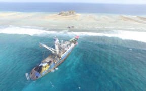 An aerial photo of the Fong Seong 666 purse seine fishing boat grounded on a reef in Majuro Atoll near a small, uninhabited island.