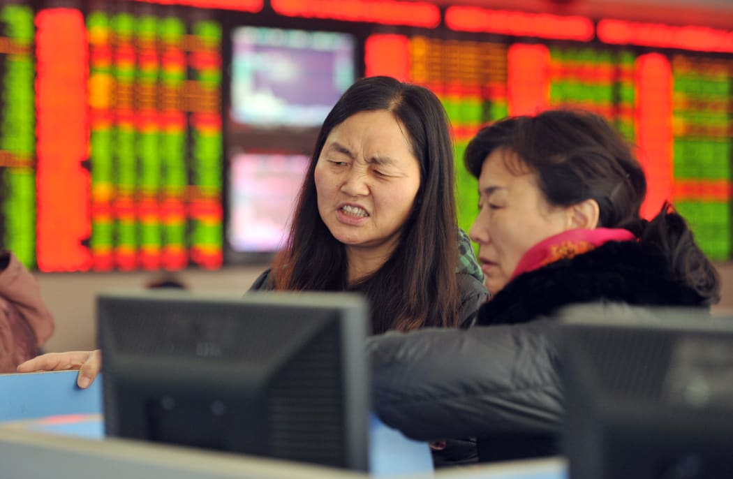 Concerned Chinese investors look at prices of shares (red for price rising and green for price falling) at a stock brokerage house