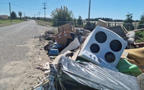 The council is refusing to take away piles of destroyed household items that line McLeod Road in Awatoto, Napier because they want to test it to find out what contaminants it contains, a resident says.