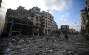 Palestinians walk amid the rubble of destroyed and damaged building in the heavily bombarded city center of Khan Yunis in the southern Gaza Strip following overnight Israeli shelling, on October 10, 2023. Israel pounded Hamas targets in Gaza on 10 October and said the bodies of 1500 Islamist militants were found in southern towns recaptured by the army in gruelling battles near the Palestinian enclave.