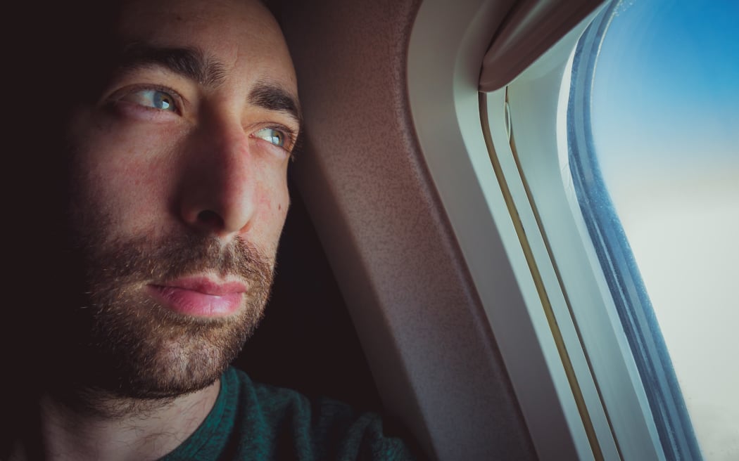 Man on plane looks out window.