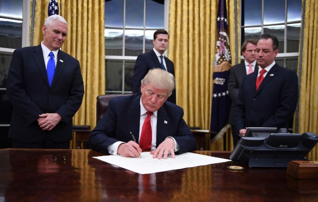 US President Donald Trump signs an executive order as Vice President Mike Pence and Chief of Staff Reince Priebus look on.