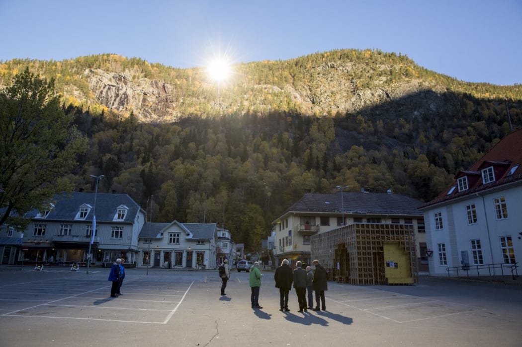People gathered on a spot in front of the town hall of Rjukan, Norway where sunshine is reflected by three giant mirrors errected on the mountainside.