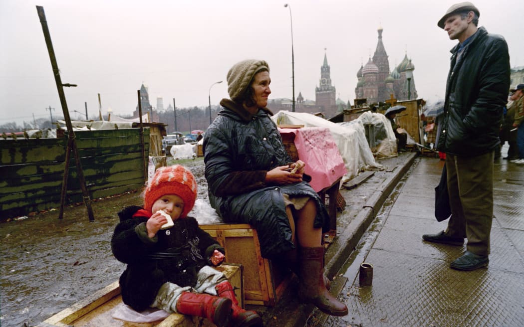 A Soviet girl bites in a slice of bread while her homeless mother and an unidentified man discuss the rationning regulations near the Saint Basil's cathedral, on 12 November 1990 on the Red Square in Moscow. Muscovites are facing difficulties in fulfilling their basic needs as the Russian market liberalisation led to a tremendous economical and social crisis and the pauperisation of the population.