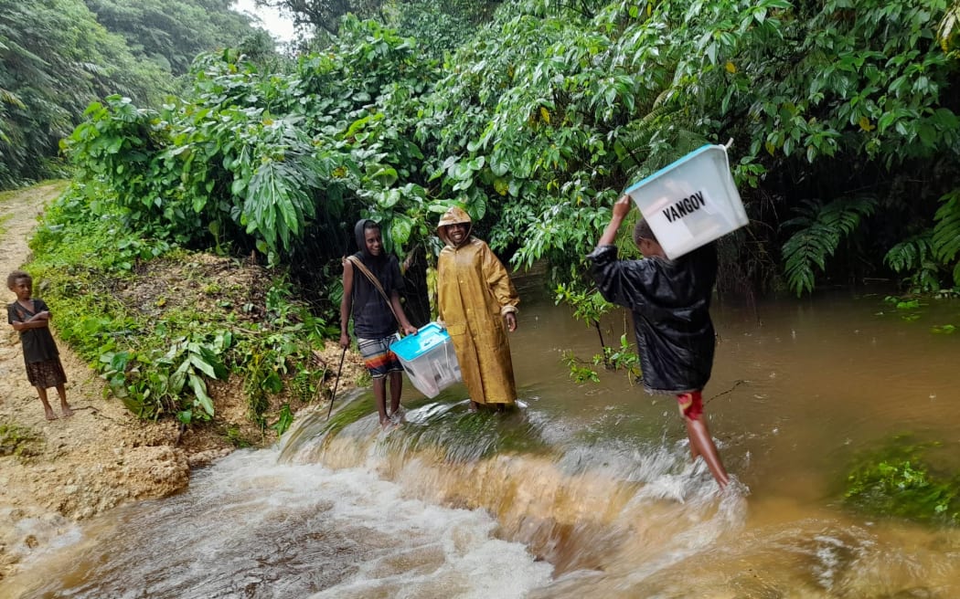 Young people of Enkul village in Central Pentecost helping police to cross Vanoleh creek with ballots boxes