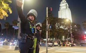 Police officers in riot gear stand near City Hall as a curfew comes into effect in Los Angeles.
