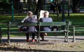 Elderly couple reading newspapers in the park