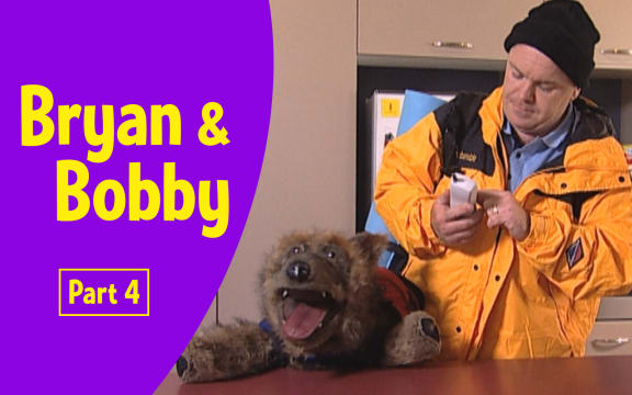 Photograph of Bryan (male adult) and Bobby (realistic large dog puppet) in a kitchen. 
Text reads   "Bryan and Bobby Part 4”