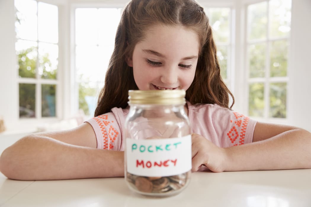 A photo of a Girl Saving Pocket Money In Glass Jar At Home