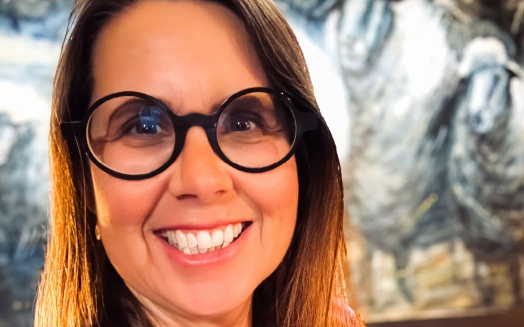 This is a close up head shot of Cally Whitman. She is smiling and wearing round, black framed glasses.