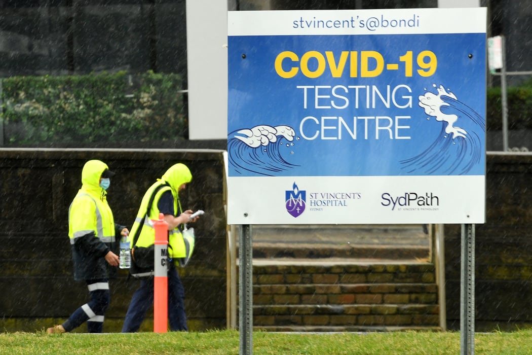 Medical officers walk past a sign board of Covid-19 testing center on Bondi Beach in Sydney on May 6, 2021.