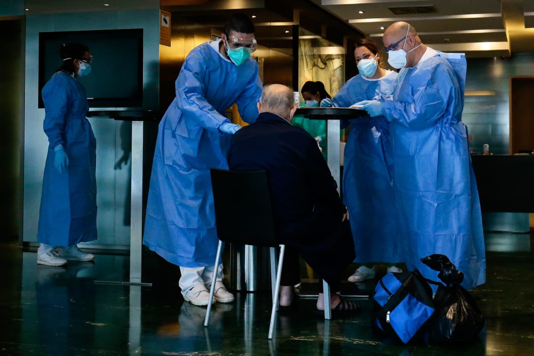 Healthcare workers attend to a COVID-19 patient upon his arrival at the Hotel Melia Barcelona Sarria.