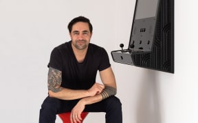 Animator Preston McNeil with an arcade game console created in collaboration with artist Joe Sheehan