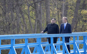 North Korea's leader Kim Jong Un (L) and South Korea's President Moon Jae-in (R) walk on a bridge after a tree-planting ceremony at the truce village of Panmunjom