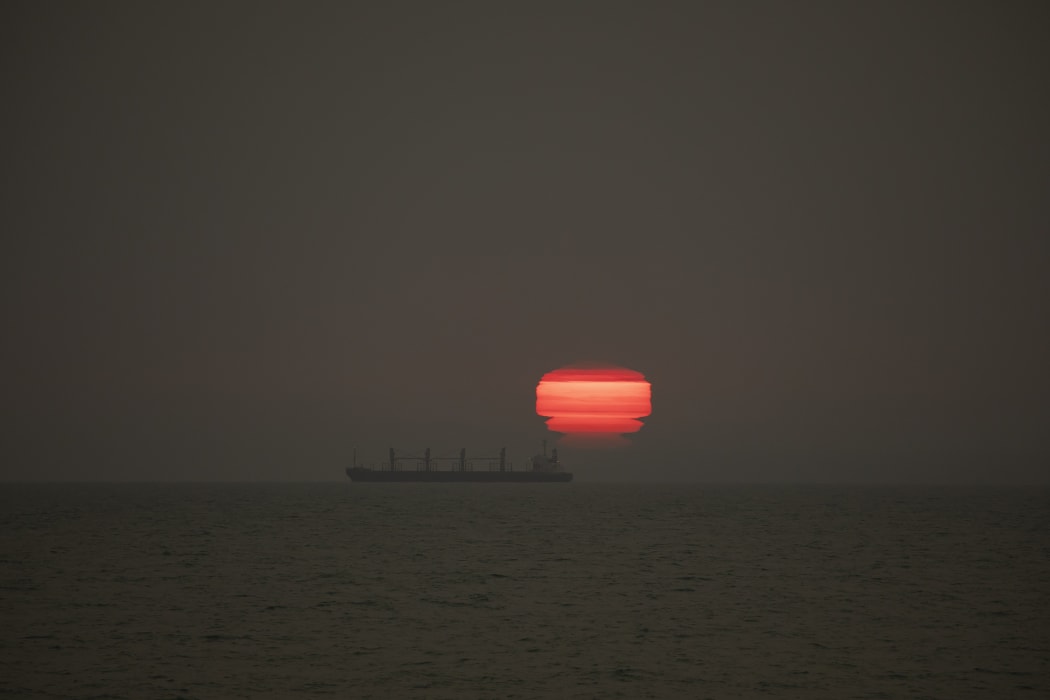 The sun rises through the smoke from Australia's bushfires drifting over New Zealand, at New Brighton Beach in Christchurch on 1 January.
