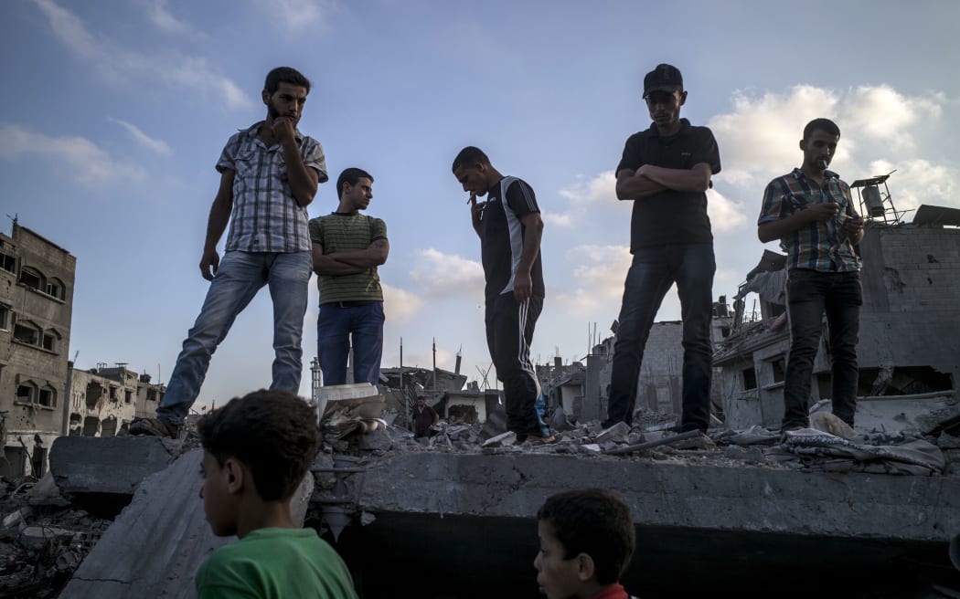 Palestinians stand on top of a destroyed building in the devastated area of Shejaiya in Gaza City.