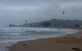Kite-surfers out in driving rain and wild winds.
