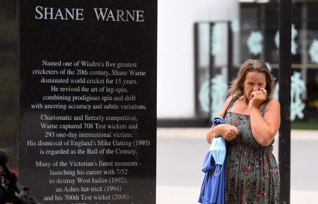 People pay their respects at the base of a statue of former Australian cricket great Shane Warne at the Melbourne Cricket Ground, in Melbourne on March 5, 2022.
