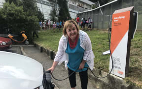Megan Woods charging a hybrid electric car.