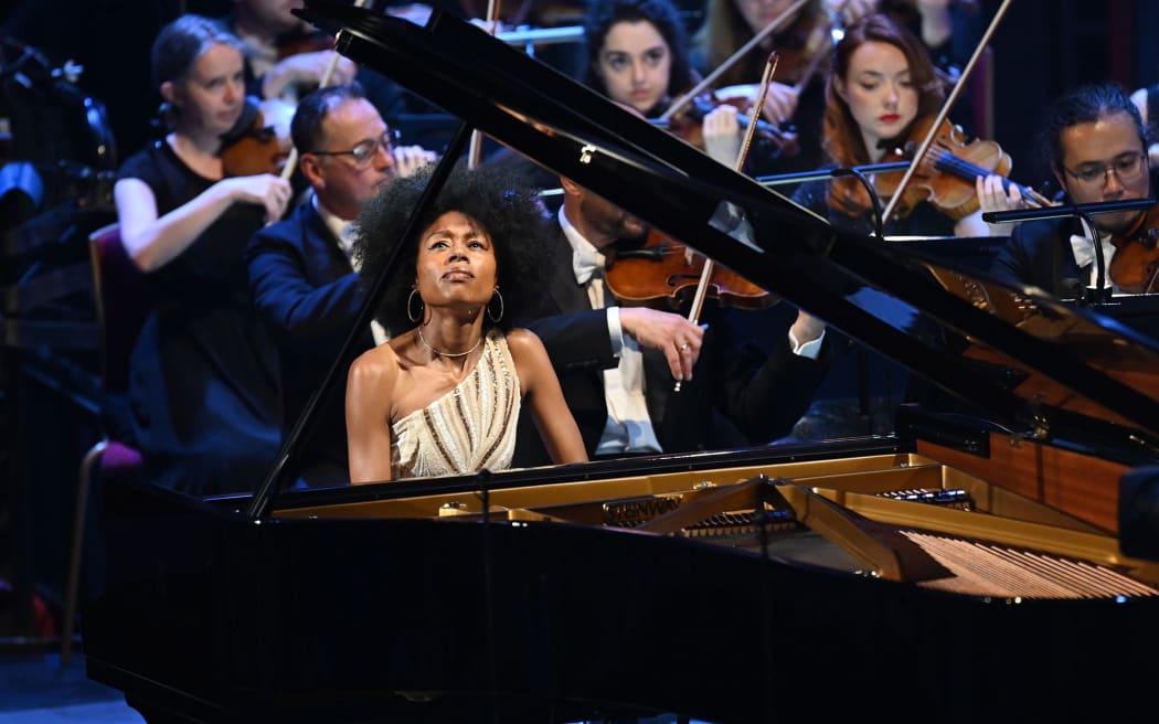 Pianist Isata Kanneh-Mason plays a grand piano with orchestra in the background.