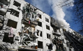 Firefighters work on a fire on a building after bombings on the eastern Ukraine town of Chuguiv on February 24, 2022.