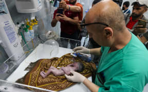 A Palestinian doctor tends to a baby born prematurely after his mother was killed during Israeli bombardment, at the Kuwait Hospital in Rafah, on the southern Gaza Strip on April 20, 2024, amid ongoing battles between Israel and the militant group Hamas. (Photo by MOHAMMED ABED / AFP)