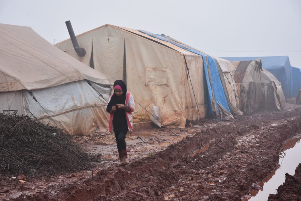 A girl walking in the mud outside her shelter at Al-Ihsan refugee camp as Syrians enduring harsh winter at the camp in Idlib, Syria on January 15, 2019.