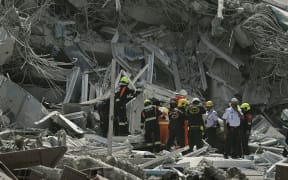 Rescue teams are seen at a construction site where a building collapsed in Bangkok on March 28, 2025, after an earthquake. A powerful earthquake rocked central Myanmar on March 28, buckling roads in capital Naypyidaw, damaging buildings and forcing people to flee into the streets in neighbouring Thailand. (Photo by Lillian SUWANRUMPHA / AFP)