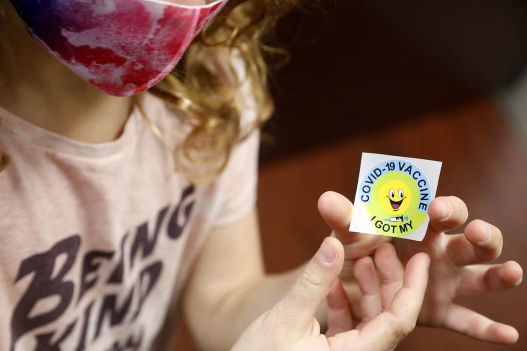 A 7 year-old child holds a sticker she received after getting the Pfizer-BioNTech Covid-19 vaccine at the Child Health Associates office in Novi, Michigan on November 3, 2021.