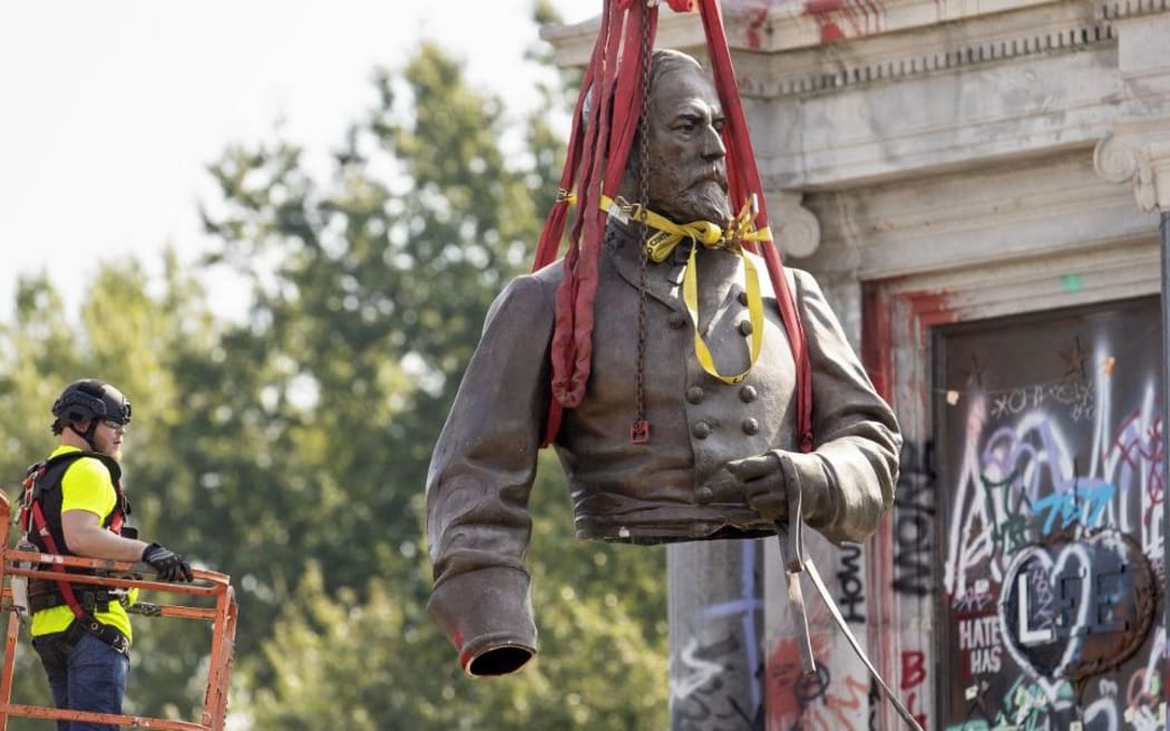 The top half of the statue of former Confederate General Robert E. Lee is lifted away after being cut off and removed from Monument Avenue in Richmond, Virginia on September 8, 2021.