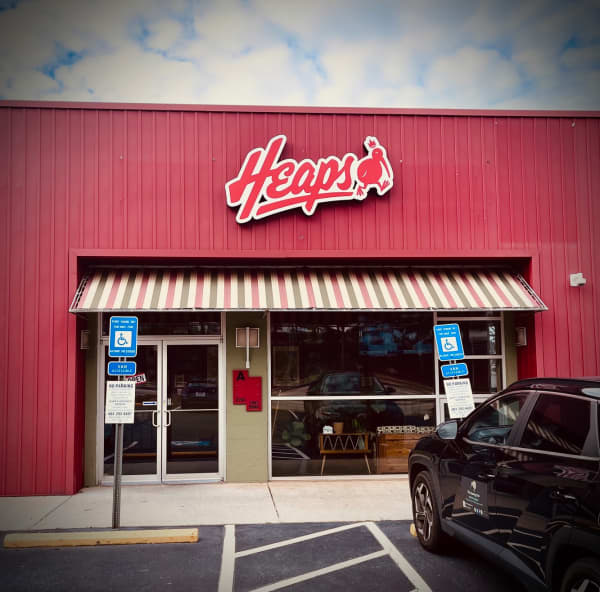The exterior of a pie shop reads 'Heaps' with an icon of a Kiwi bird next to it.