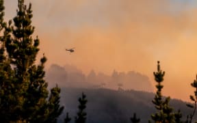 A helicopter can be seen attacking the vegetation fire at Christchurch's Port Hills on 14-15 February 2024.