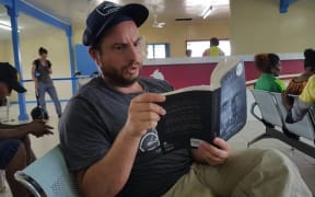 Dan Ilic reading Behrouz Boochani's book at the Manus airport.