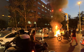 Demonstrators gather around a burning barricade during a protest for Mahsa Amini, a woman who died after being arrested by the Islamic republic's "morality police", in Tehran on September 19, 2022. - Fresh protests broke out on September 19 in Iran over the death of a young woman who had been arrested by the "morality police" that enforces a strict dress code, local media reported. Public anger has grown since authorities on Friday announced the death of Mahsa Amini, 22, in a hospital after three days in a coma, following her arrest by Tehran's morality police during a visit to the capital on September 13. (Photo by AFP)