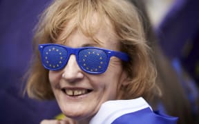 A pro-EU demonstrator waves a Union flag whilst wearing European Union flag-themed attire during an anti-Brexit protest.