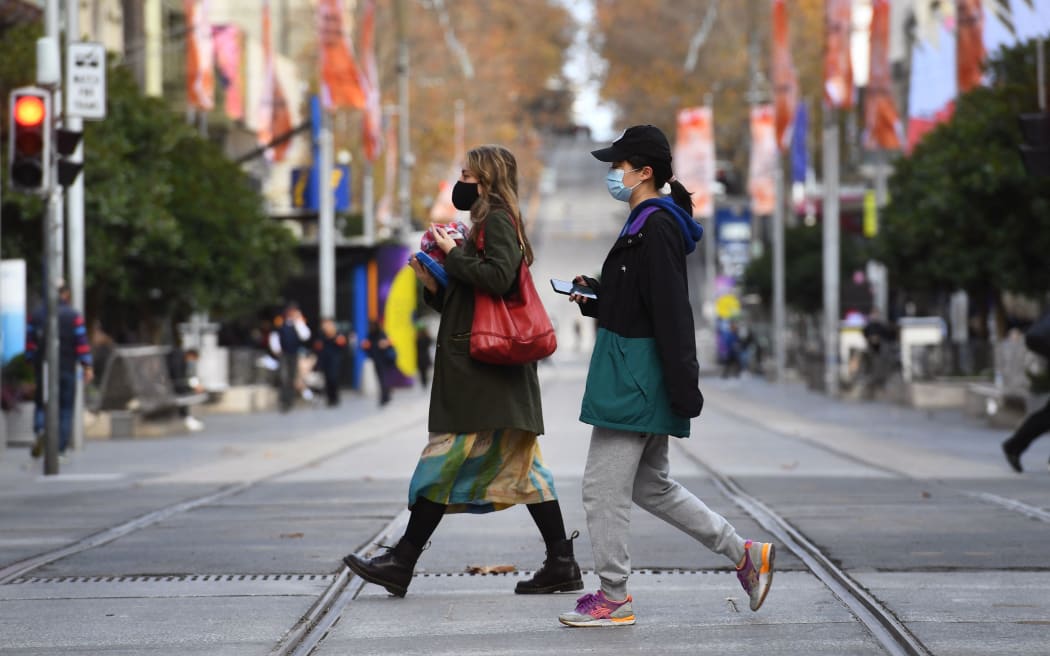 People wearing masks cross an almost empty shopping street in Melbourne on May 26, 2021, as Australia's second biggest city scrambles to contain a growing Covid-19 outbreak. (Photo by William WEST / AFP)