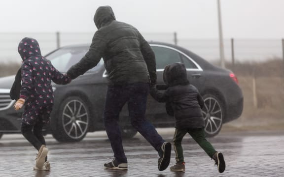 picture of a family who is crossing a street while it is heavy raining