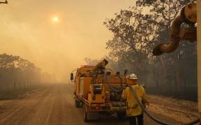 Firefighters refill their water from a water tanker in Pacific Drive in Deepwater National Park area of Queensland.