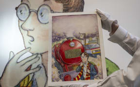 An art handler holds Thomas Taylor’s original cover art for J.K. Rowling's Harry Potter and the Philosopher’s Stone at Sotheby’s in New York on June 25, 2024. The item is the most valuable Harry Potter material ever offered at an auction and is estimated to be auctioned between $400,00-600,000 during the Fine Books & Manuscripts Auction in June. (Photo by ANGELA WEISS / AFP)