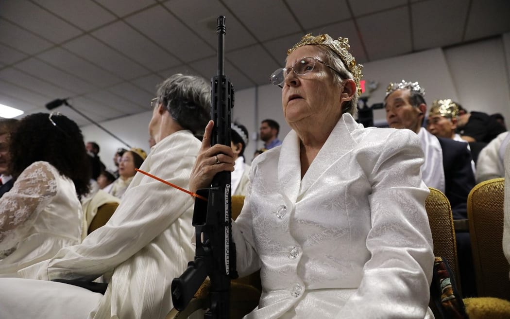 NEWFOUNDLAND, PA - FEBRUARY 28: A woman holds an AR-15 rifle during a ceremony at the World Peace and Unification Sanctuary on February 28, 2018 in Newfoundland, Pennsylvania. The controversial church, which is led by the son of the late Rev. Sun Myung Moon, believes the AR-15 symbolizes the "rod of iron" in the biblical book of Revelation, and it has encouraged couples to bring the weapons to a "commitment ceremony" or "Perfection Stage Book of Life Registration Blessing". Officials in the rural area in the Pocono Mountains have reportedly told elementary school parents that their children will be relocated on Wednesday to accommodate the AR-15 ceremony. The semiautomatic rifles are similar to the weapon used in a Florida high school shooting on February 14.   Spencer Platt/Getty Images/AFP (Photo by SPENCER PLATT / GETTY IMAGES NORTH AMERICA / Getty Images via AFP)