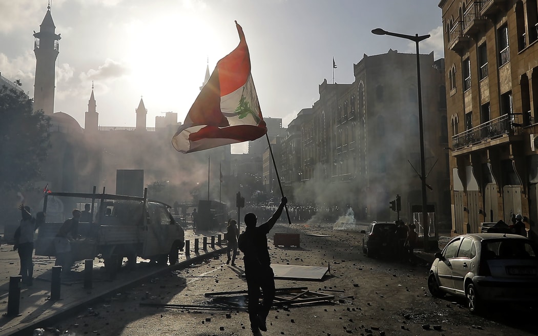 A Lebanese protester waves the national flag during clashes with security forces in downtown Beirut on August 8, 2020,