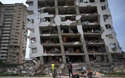 Rescue workers are seen next to a destroyed building in La Guaira, Venezuela on July 4, 2026, following the June 24 twin earthquakes. With little hope of finding loved ones alive, frustrated families of those affected by Venezuela’s double earthquakes clamor for help to recover their loved one’s bodies as uncertainty grows over the death toll from the tragedy. (Photo by Raul ARBOLEDA / AFP)