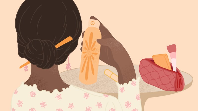 A woman holds up a spray can from a bag of cosmetics.