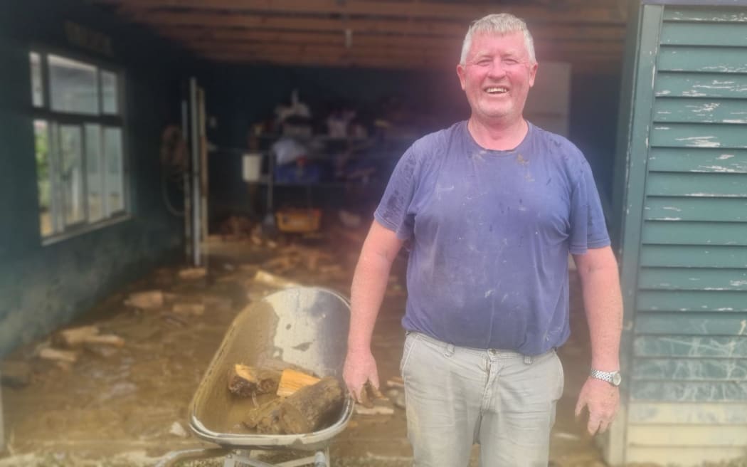 Martin Hegason cleans up his flooded garage. His fence line with watermark showing how high the river rose.